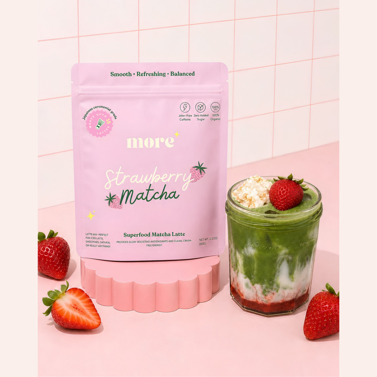 Layered strawberry matcha latte made with More Superfoods blend beside fresh strawberries
