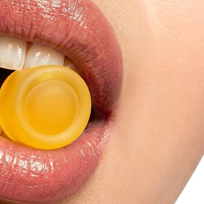 Close up of a yellow lemon flavoured Vitalis Living NAC glycine gummy on lips